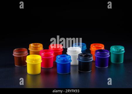 Nahhintergrund geöffneter kleiner Gouache-Farbgläser auf schwarzer Oberfläche Stockfoto