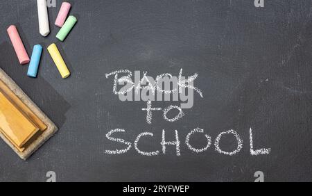 Gruppe von farbigen Kreiden, Radiergummi und handgezeichneter Phrase Back to School auf Tafel Stockfoto