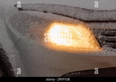 Schneebedeckter Scheinwerfer eines weißen oder silbernen zivilen Autos Stockfoto