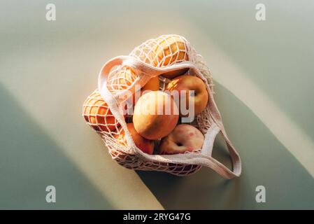 Frische reife Pfirsiche im Fadenbeutel bei Sonnenlicht. Zero Waste Konzept, gesunde Lebensmittel. Draufsicht, flach. Stockfoto