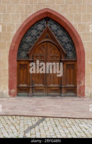 Gewölbte antike Kirche Holztür mit schwarzen Eisenornamenten in einer Steinwand. Stockfoto