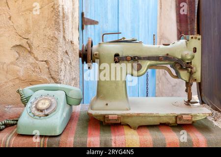 Antike alte Gegenstände, die auf einem traditionellen Markt in Dubai gefunden wurden. Nähmaschine und analoges Telefon. Stockfoto