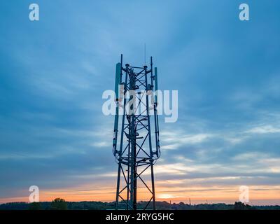 3G, 4G, 5G Mobiltelefon-Basisstation Tower. Entwicklung des Kommunikationssystems im nicht-städtischen Waldgebiet mit dunklem Sonnenuntergang oder Su Stockfoto