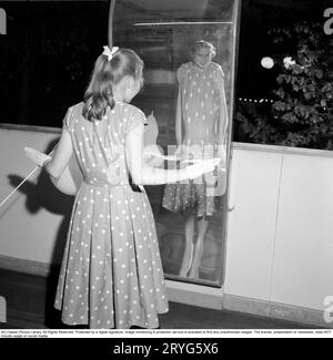 Gröna Lund Vergnügungspark in den 1950er Jahren Ein Mädchen im Teenageralter spaziert durch den Lachraum. Ein Spiegelhaus, in dem Sie herumlaufen und sich darin spiegeln können. Je nach Spiegeltyp können Sie groß oder kurz, fett oder dünn sein. Die Erklärung ist, dass die Spiegel entweder konkav oder konvex oder eine Kombination aus beiden sind. 31. Mai 1958. Conard Ref. 3760 Stockfoto