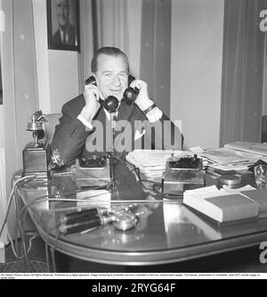 In den 1940er Jahren Ein Mann in einem Büro mit zwei Telefonen, die beschäftigt sind und gleichzeitig in zwei Telefonen sprechen. Schweden 1945. Kristoffersson ref N12-4 Stockfoto