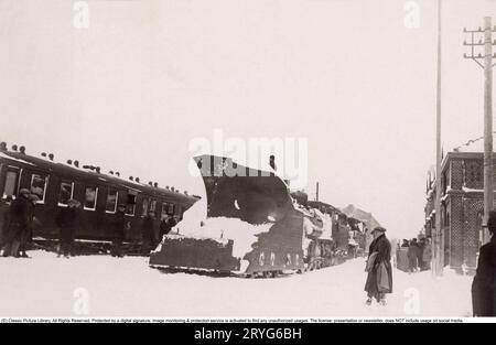 Schneesturm in den 1920er Jahren Ein Schneesturm hat Südschweden und die Region Scania getroffen, und hier steht der schneebedeckte Westküstenzug am Bahnhof Svalöv im Februar 1929. Die Bereitschaft der Staatsbahnen ist jedoch hoch und vor der Dampflokomotive ist ein Schneepflug eines größeren Modells montiert, der den Schnee von den Schienen vor dem Zug wegpflügt. Auf den Plattformen laufen die Menschen im tiefen Schnee herum. Stockfoto
