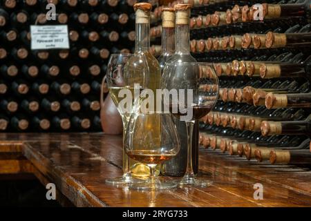 Eine Zusammenstellung von Flaschen verschiedener Weinsorten mit einem Weinkeller im Hintergrund. Weinprobe Stockfoto