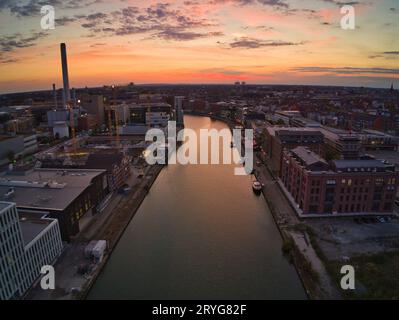 Luftaufnahme eines von Gebäuden umgebenen Hafens mit der Abendsonne im Hintergrund in Münster Stockfoto