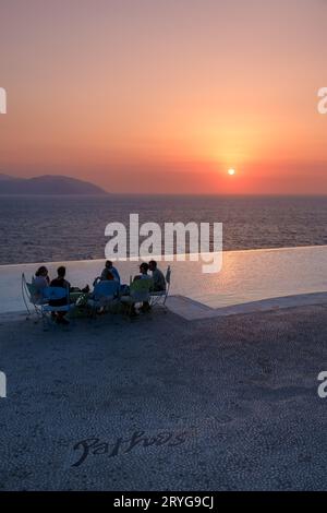 IOS, Griechenland - 8. September 2023 : Touristen genießen Drinks und einen atemberaubenden Blick auf die Ägäis mit einem orangen Sonnenuntergang in einer Loungebar in Griechenland Stockfoto