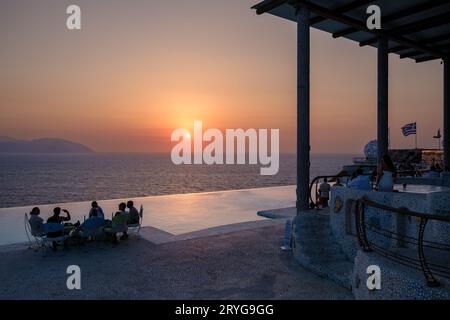 IOS, Griechenland - 8. September 2023 : Touristen genießen Drinks und einen atemberaubenden Blick auf die Ägäis mit einem orangen Sonnenuntergang in einer Loungebar in Griechenland Stockfoto