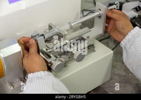 Nahaufnahme von Händen, die an einer Maschine in einem medizinischen Produktionslager für Spritzen arbeiten Stockfoto