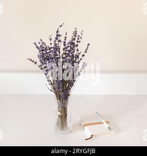 Lavendelblumen in einer Vase auf einem Tisch mit Notizbuch und Stift, Frühlingsnostalgisches Konzept Stockfoto