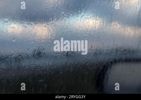 Regen tropft Wasser auf das Autofenster. Blick von der Oberfläche aus dem Glasfensterwagen mit Regenwasser an einem regnerischen Tag Stockfoto