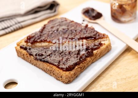 Nahaufnahme von Vollkornbrot-Toast-Sandwich und Himbeer-Bio-Marmelade auf Holztisch Stockfoto