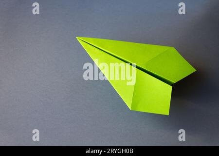 Grünpapierflugzeug Origami isoliert auf grauem Hintergrund Stockfoto