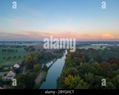 Panorama des dramatischen und farbenfrohen Himmels über Felder, Bäume und Fluss oder Kanal von einer Drohne aus während Sonnenuntergang oder Sonnenaufgang Stockfoto