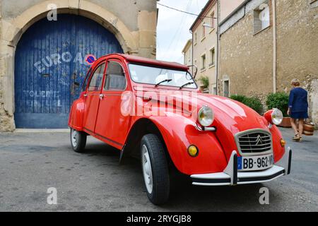 HERAULT (34). SAINT-CHINIAN. RED CITROEN CAR 2CV PARKTE VOR EINER GARAGE Stockfoto