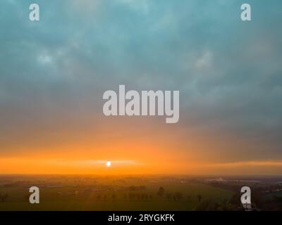 Blick aus der Vogelperspektive auf endlose üppige Weiden und Ackerland Belgiens unter einem dramatischen, farbenfrohen Sonnenuntergang. Wunderschönes antwerpener Land Stockfoto