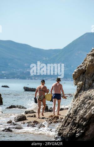 Ein älteres oder mittleres Paar, das an einem Strand am Südufer der griechischen Insel zante oder zakynthos in griechenland spaziert. Stockfoto