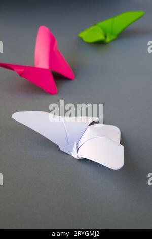 Grünes, rosafarbenes und weißes Papier mit Schmetterling Origami isoliert auf grauem Hintergrund Stockfoto