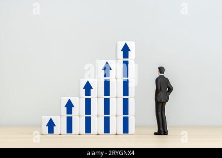 Eine Geschäftsfigur, die auf Bausteine mit blauen Pfeilen schaut. Wachstum, Wachstum von Unternehmen und Wirtschaft. Speicherplatz kopieren Stockfoto