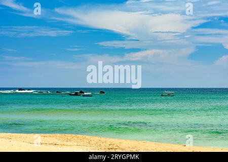 Hölzerne Fischerboote auf dem farbenfrohen Wasser des Strandes von Itapua in Salvador Stockfoto