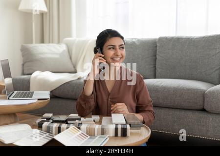 Lächelnde indische Innenarchitektin, die am Telefon spricht, Klientin berät Stockfoto