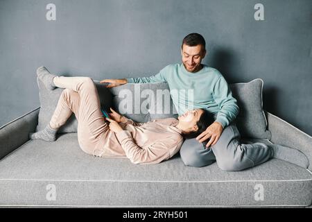 Junge glückliche Paare, die sich auf dem Sofa entspannen und ihre Zeit zu Hause verbringen Stockfoto