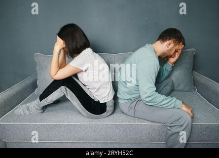 Ein junges Paar, das sich auf der Couch sitzend und beleidigt aussah, während es einen Streit hatte Stockfoto