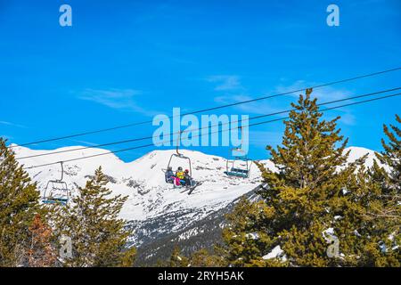 Eine Gruppe von Skifahrern, die mit dem Sessellift in Andorra, Pyrenäen, fahren Stockfoto