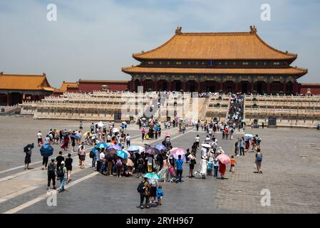 Touristenmassen mit Schirmen am Eingang der berühmten Verbotenen Palaststadt in Peking, China. Stockfoto