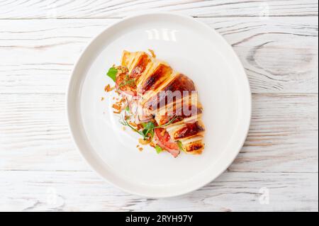 Croissant Sandwich mit Frischkäse, Schinken und Rucola auf weißem Teller, grauer Hintergrund, Draufsicht. Gesundes Frühstückskonzept. Hochwertige Fotos Stockfoto