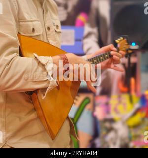 Mann spielt Balalaika im Musikladen. Nahaufnahme. Stockfoto