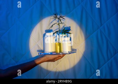 Schlafkapseln mit einem Zweig Cannabis, Hand im Mondschein auf einer Decke, Melatonins Kampf gegen Schlaflosigkeit Stockfoto