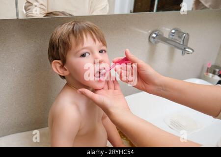 Ihr Kleinkind lernt mit Hilfe ihrer Mutter im Badezimmer, die Zähne zu putzen. Kind im Alter von zwei Jahren (zweijähriger Junge) Stockfoto