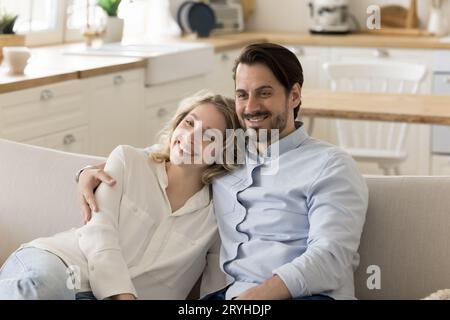 Lächelnde Frau und Mann umarmen sich auf dem Sofa Stockfoto