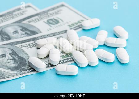 Kostenkonzept Medizin. US-Dollar-Scheine und Medizinpillen auf blauem Hintergrund Stockfoto