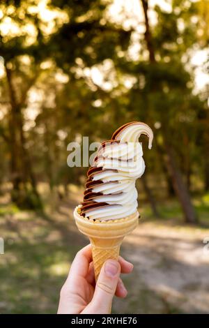 Weibliche Hand mit köstlichem Eis aus amerikanischer Vanille-Schokolade. Leckeres hausgemachtes Eiscreme-Eis in der Waffelhülle. Gluten fr Stockfoto