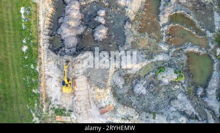 Gelber Planierschild führt Erdarbeiten durch – Luftaufnahme. Gelber Raupentraktor hake den Boden, um ein Asphaltroa zu bauen Stockfoto