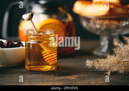 Honig im Glas mit hölzernem Honiglöffel auf einem Serviertisch Stockfoto