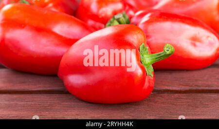 Rote Paprika auf Holztisch Nahaufnahme. Rote Paprika in einem Stapel Stockfoto