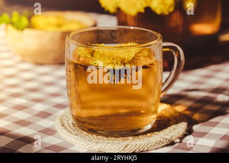 Löwenzahnblume gesunder Tee in Glas Teekanne und Glasbecher auf dem Tisch. Köstlicher heißer Kräutertee aus frischen Löwenzahn-Blumen bei Ho Stockfoto