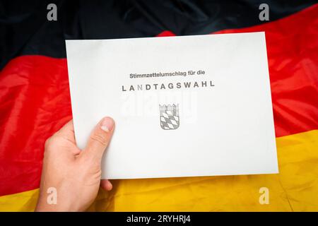 Augsburg, Bayern, Deutschland. September 2023 29. Dokumente zur Landtagswahl in Bayern am 8. Oktober 2023 unter deutscher Flagge. Stimmpapierumschlag zur Landtagswahl in Bayern *** Unterlagen zur Landtagswahl am 8. Oktober 2023 auf einer Deutschland Flagge. Stimmzettel Umschlag zur Landtagswahl Credit: Imago/Alamy Live News Stockfoto