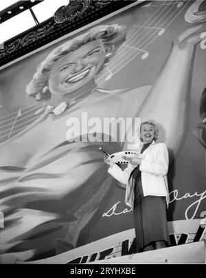 DORIS DAY zeichnet ein großes Plakatposter, auf dem sie ihren neuesten Film LUCKY ME 1954, den Regisseur JACK DONOHUE, Anfang März 1954 auf dem Wilshire Boulevard in Hollywood für Warner Bros. Wirbt Stockfoto