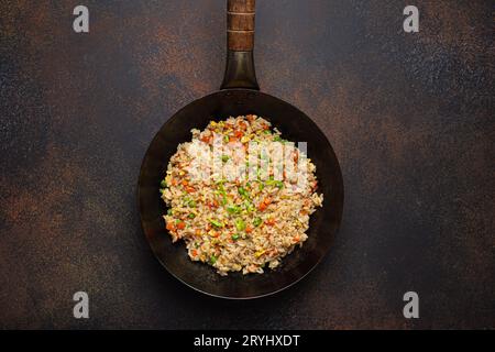 Authentischer chinesischer und asiatischer gebratener Reis mit Ei und Gemüse in Wokobersicht, rustikaler Betontischhintergrund. Traditionelles Di Stockfoto