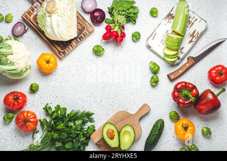 Frisches Gemüse, Schneidebretter aus Holz und Messer auf weißem Küchentisch mit Blick von oben. Kochen vegetarisches Essen von gesund Stockfoto