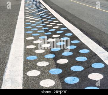 Fußgängerübergang auf Asphaltstraße mit blauen und weißen Punkten Stockfoto