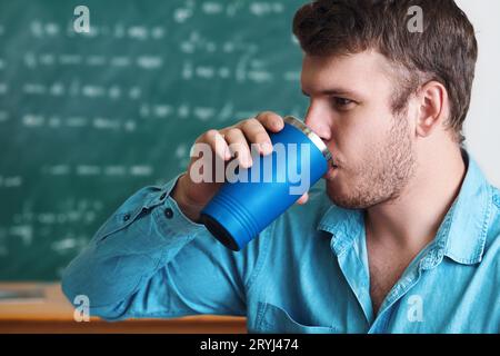 Ein Schüler trinkt ein Getränk oder Kaffee aus einem Thermosbecher. Seitenansicht. Modell mit Kopierraum. Wasserhaushalt. Vorteile des Trinkens. Stockfoto