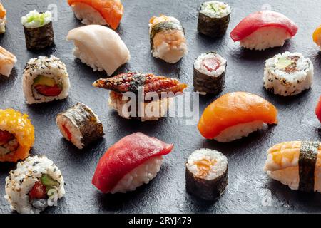 Sushi-Sortiment. Brötchen, Maki, Nigiri auf schwarzem Hintergrund, japanisches Essen Stockfoto