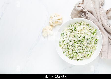 Roher Blumenkohlreis oder Couscous mit Dill in weißer Schüssel, gesunde kohlenhydratarme Gemüsebeilage für Keto-Ernährung und Gesundheit Stockfoto